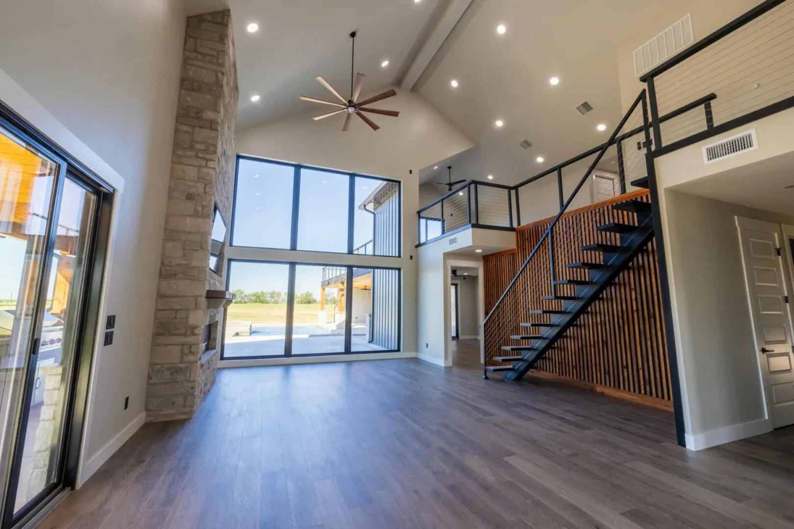 Modern living room with large windows and staircase.