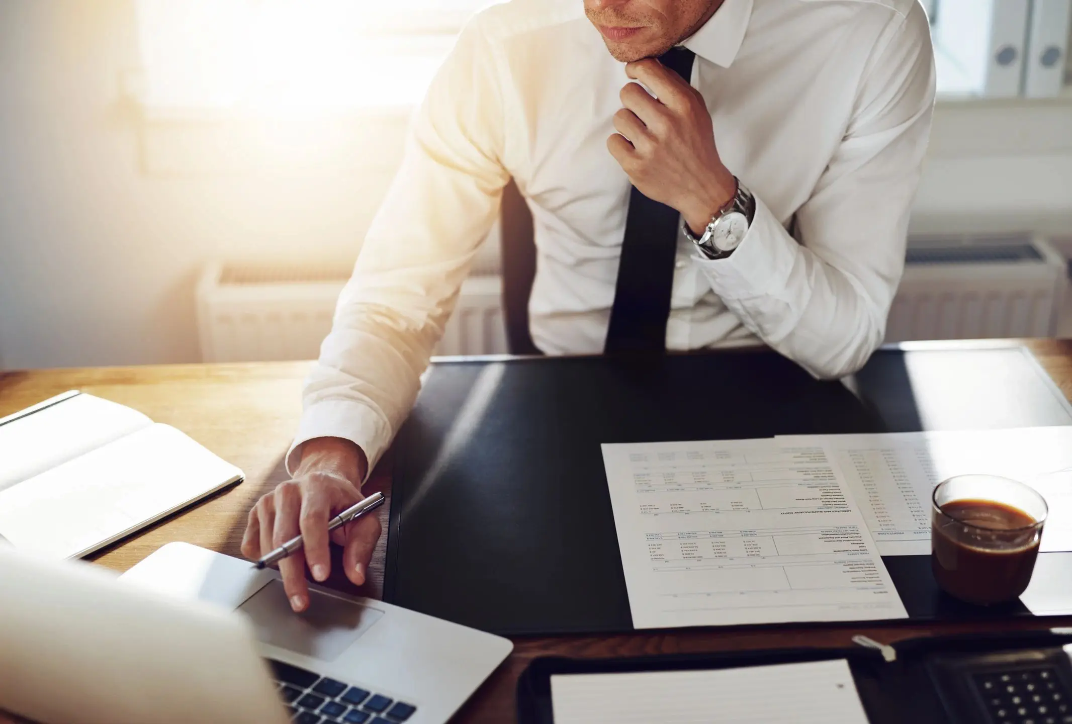 Businessman using smartphone and laptop at office desk.