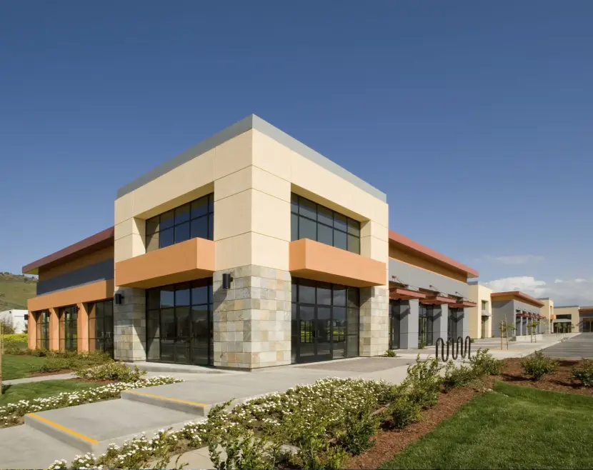 Modern commercial building with glass windows and stone accents under a clear blue sky.