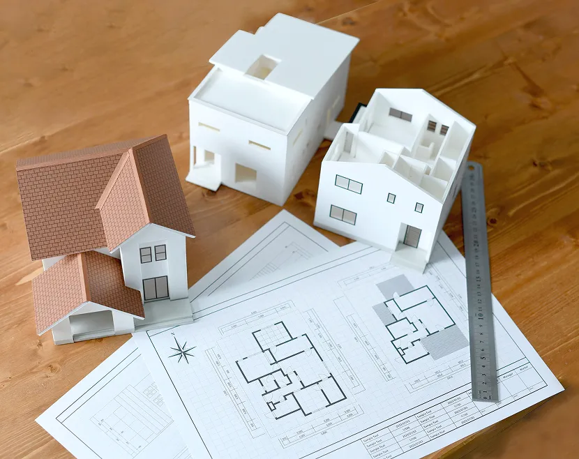 Architectural models and blueprints on wooden table.
