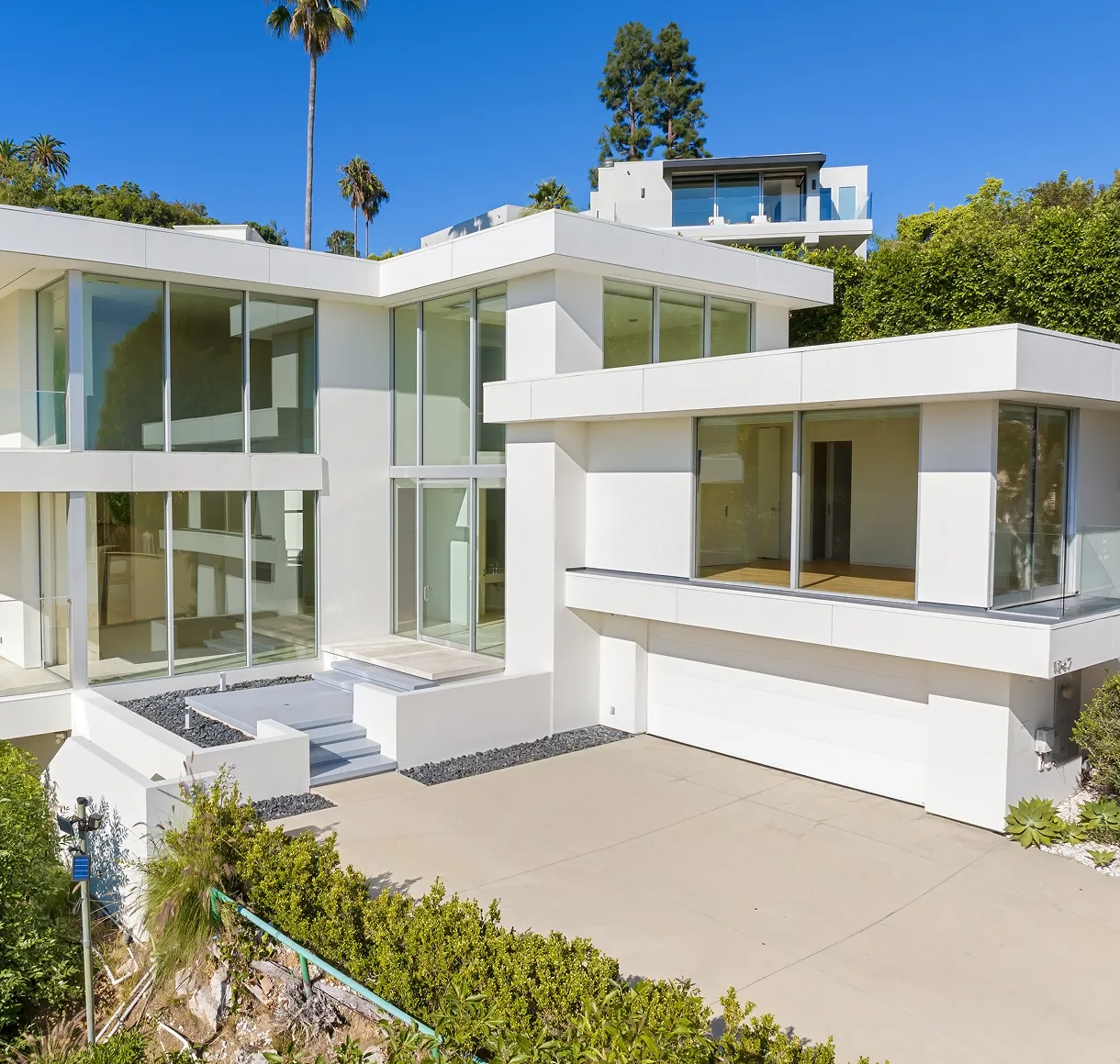 Modern white house with large glass windows.